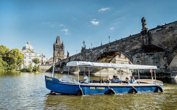 Sightseeing cruise boat on Vltava River near Charles Bridge, Prague.