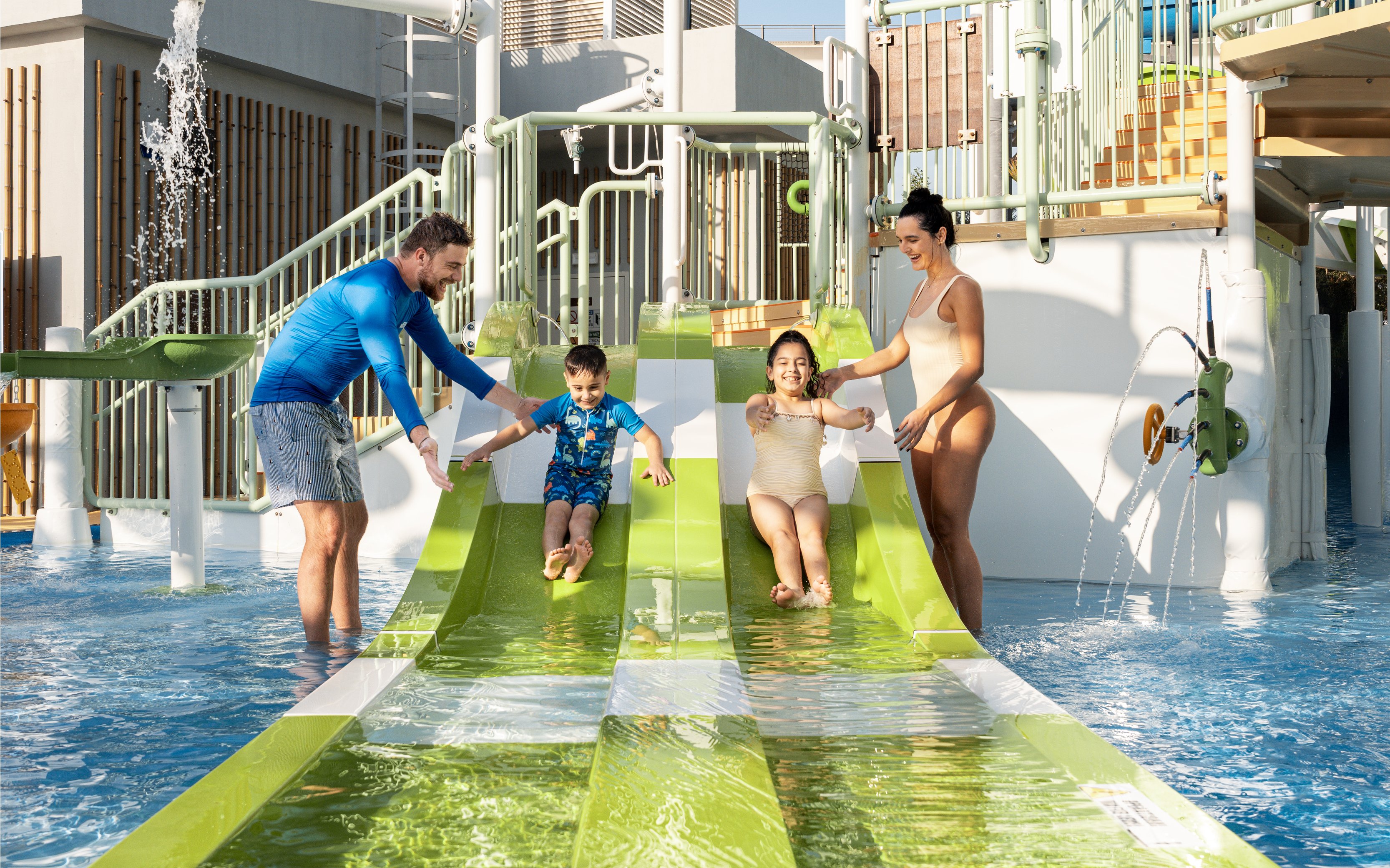 Parents supervising children on water slides at Grand Hyatt waterpark, Dubai.