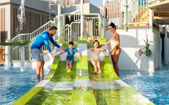 Parents supervising children on water slides at Grand Hyatt waterpark, Dubai.