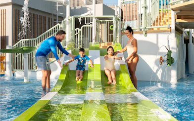 Parents supervising children on water slides at Grand Hyatt waterpark, Dubai.
