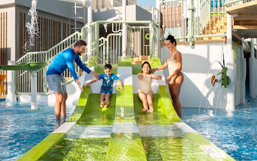 Parents supervising children on water slides at Grand Hyatt waterpark, Dubai.