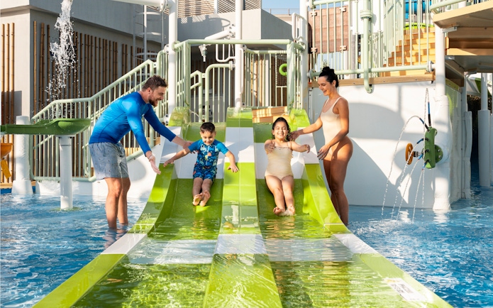 Parents supervising children on water slides at Grand Hyatt waterpark, Dubai.
