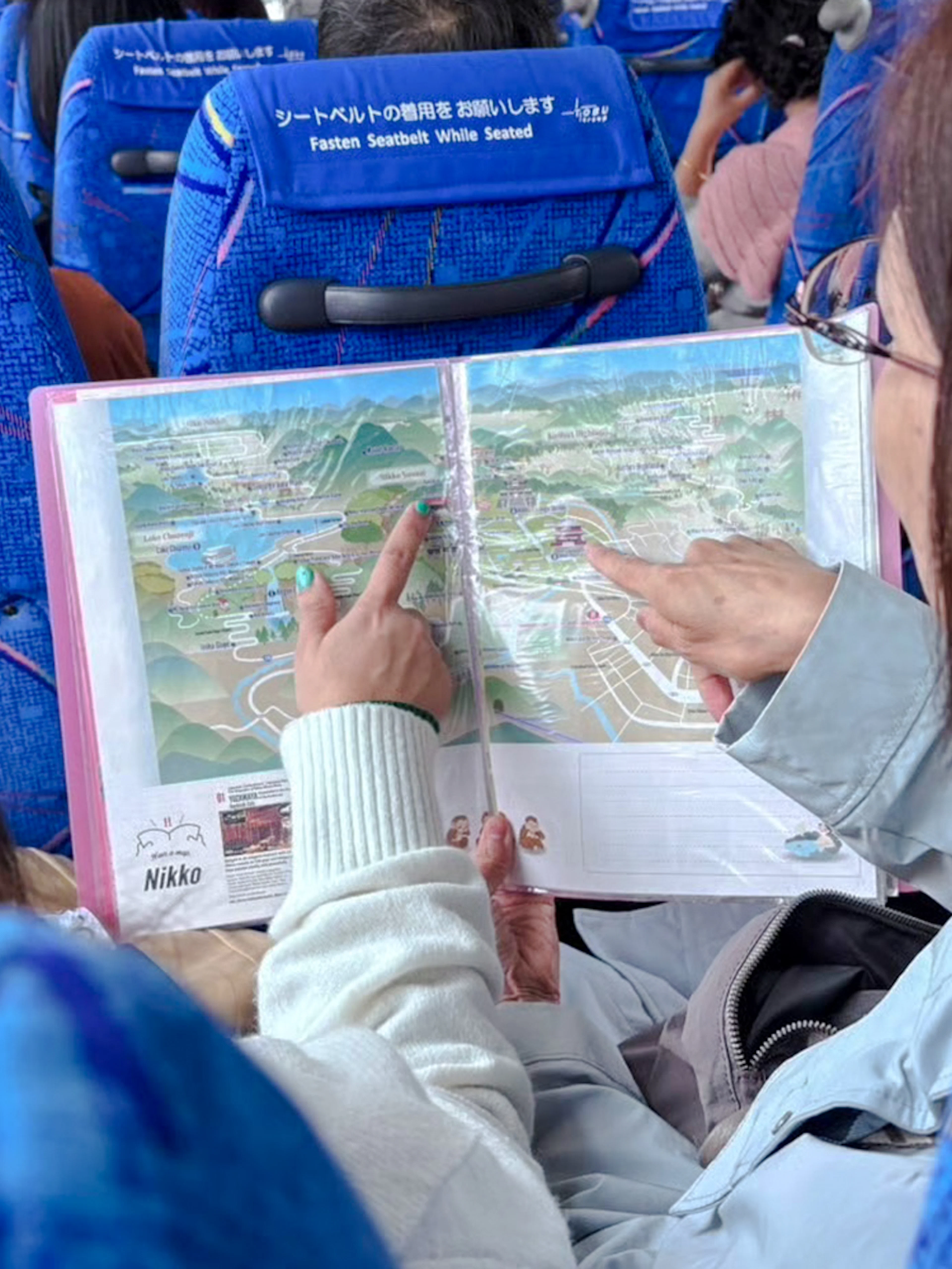 Tourists examining Nikko Pass map on a bus in Japan.