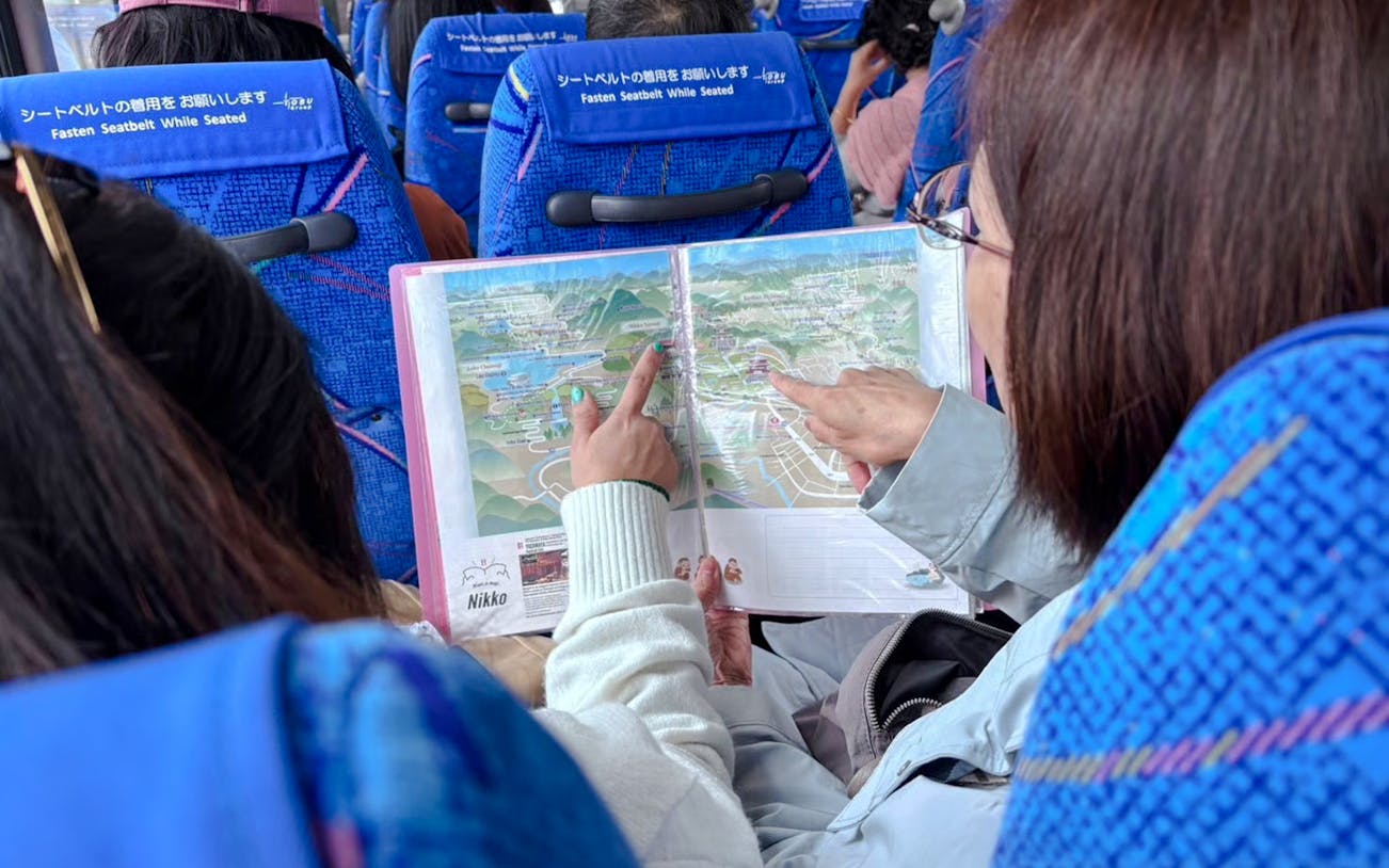 Tourists examining Nikko Pass map on a bus in Japan.