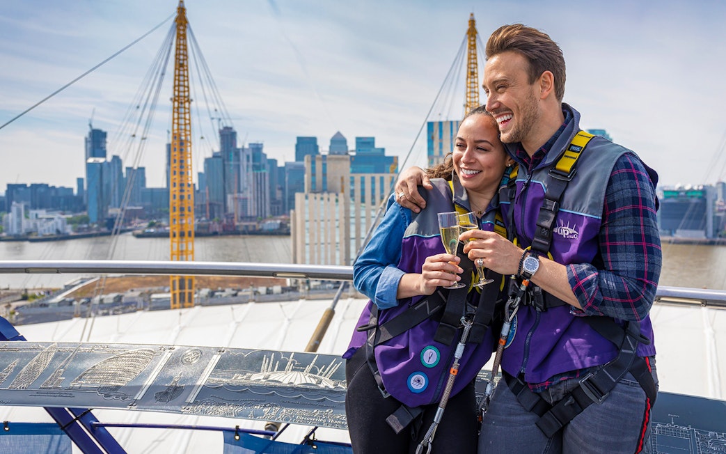 Participants enjoy champagne atop The O2 Arena with London skyline in the background.