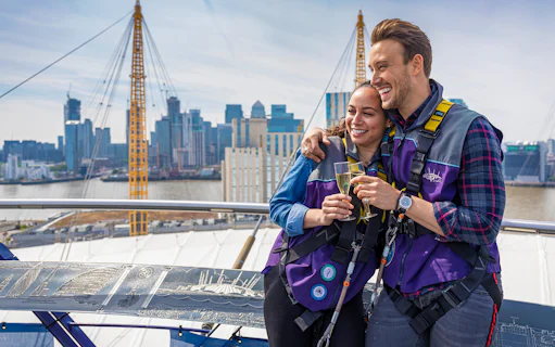 Participants enjoy champagne atop The O2 Arena with London skyline in the background.