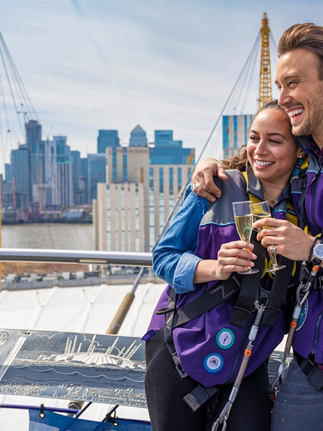Participants enjoy champagne atop The O2 Arena with London skyline in the background.