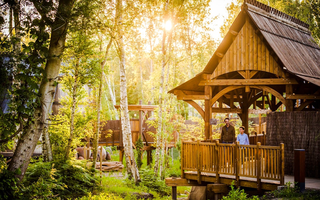 Visitors on a wooden bridge surrounded by trees at Asterix Park.