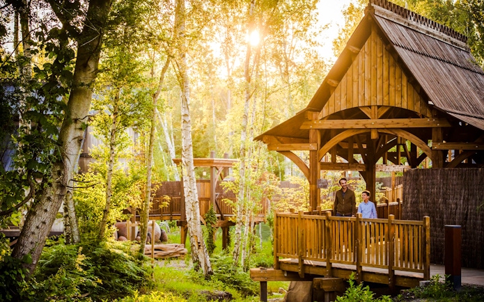 Visitors on a wooden bridge surrounded by trees at Asterix Park.
