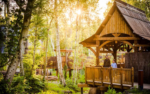 Visitors on a wooden bridge surrounded by trees at Asterix Park.