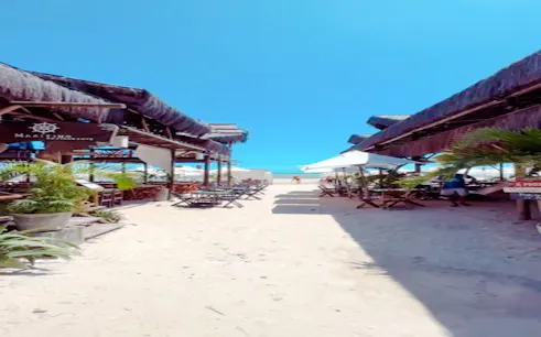Beachside dining area with tables and umbrellas leading to Flecheiras beach, Sao Paulo.