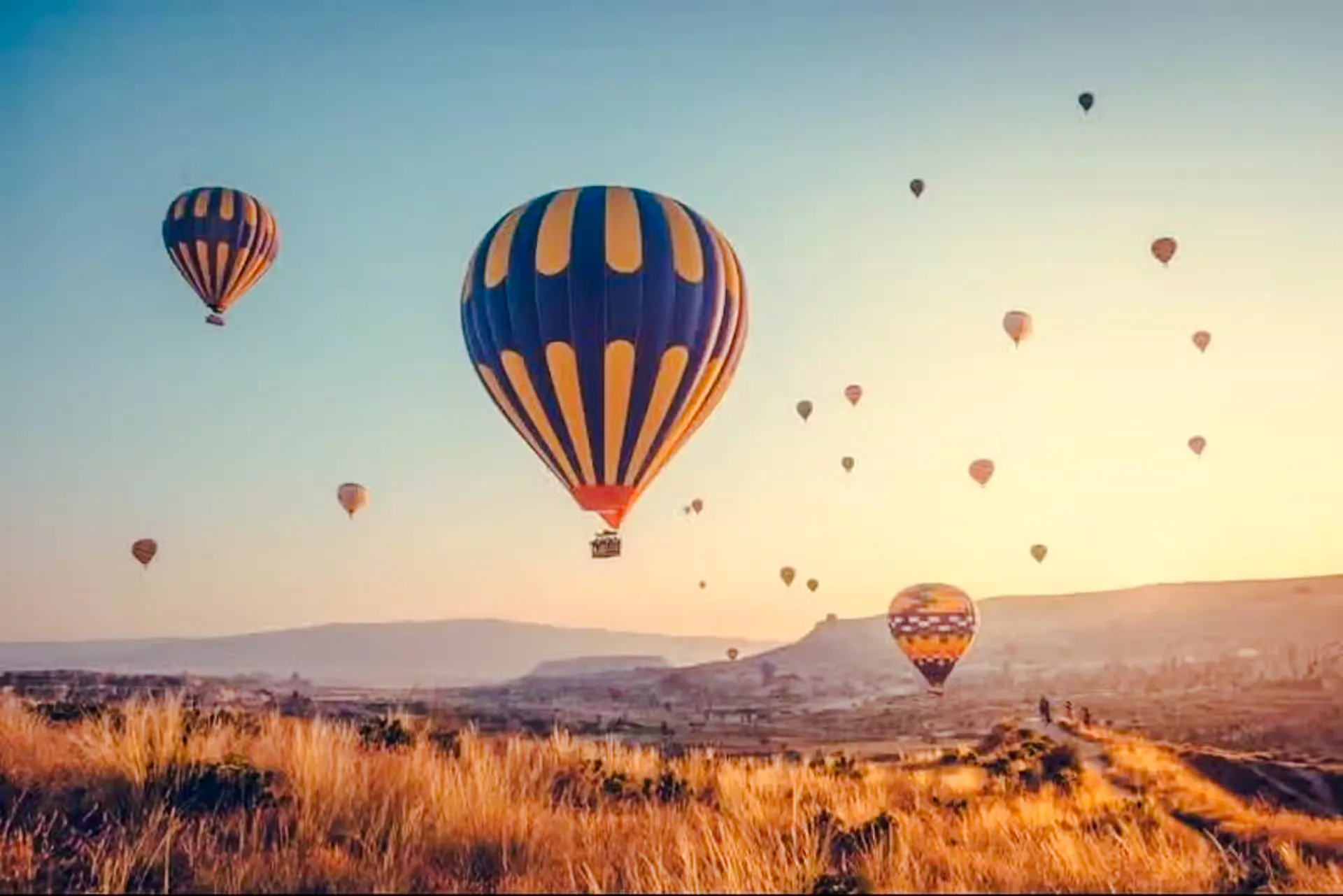 Hot air balloons over Cappadocia landscape at sunrise during Red Valley hike.