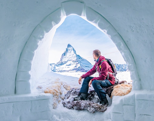 Person sitting in an ice cave, viewing the Matterhorn at Glacier Paradise, Switzerland.