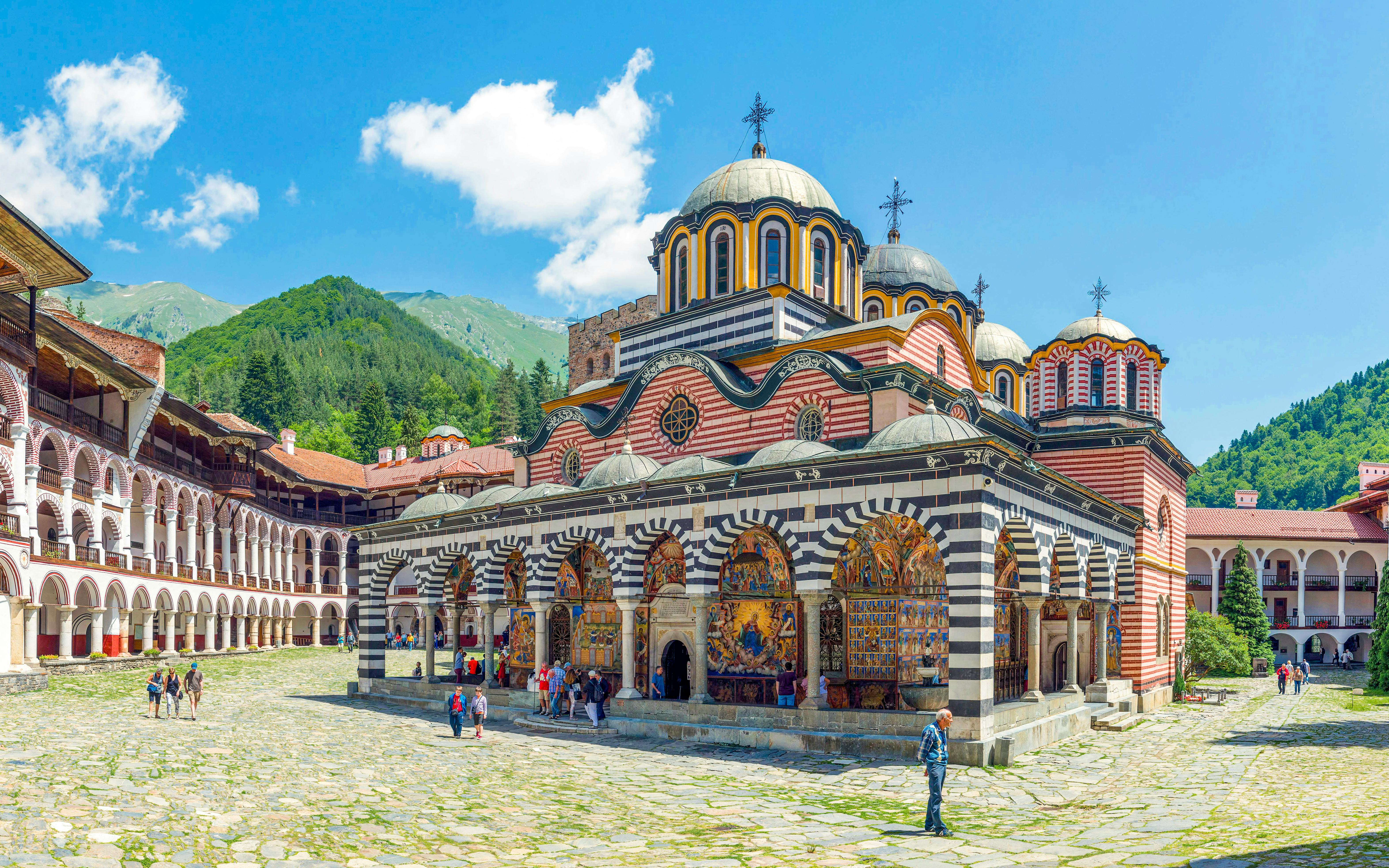 Rila Monastery courtyard with colorful frescoes and domed church, Bulgaria.