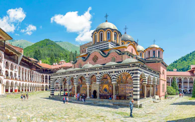 Rila Monastery courtyard with colorful frescoes and domed church, Bulgaria.