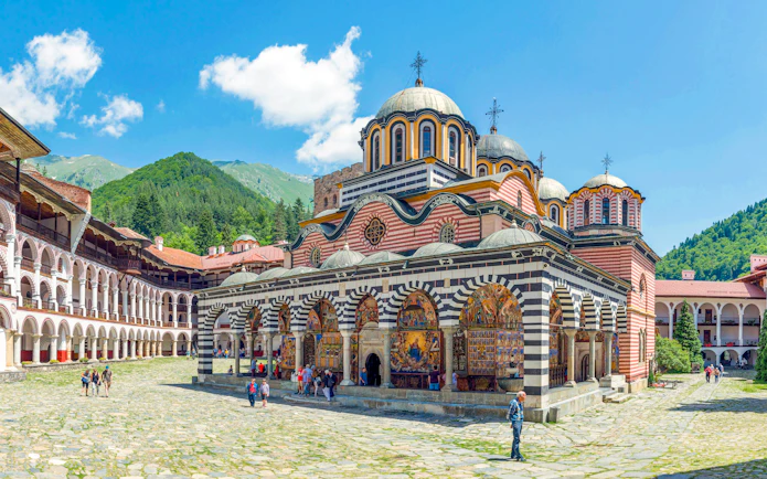 Rila Monastery courtyard with colorful frescoes and domed church, Bulgaria.