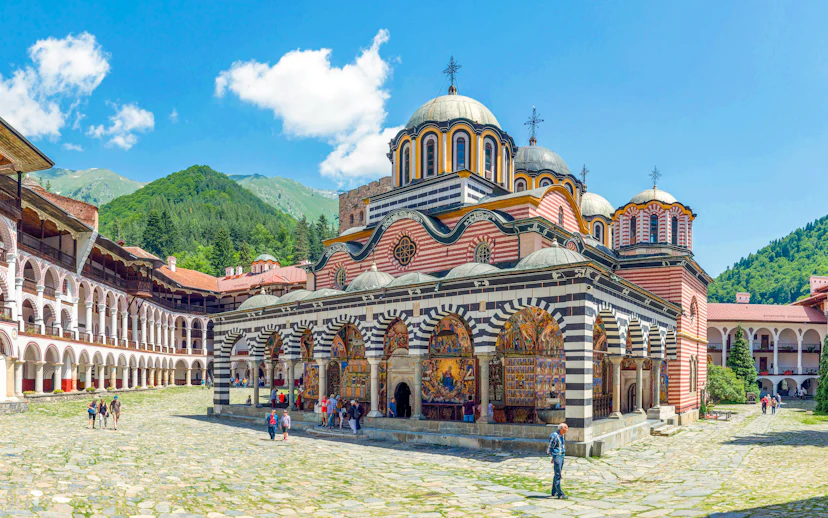 Rila Monastery courtyard with colorful frescoes and domed church, Bulgaria.