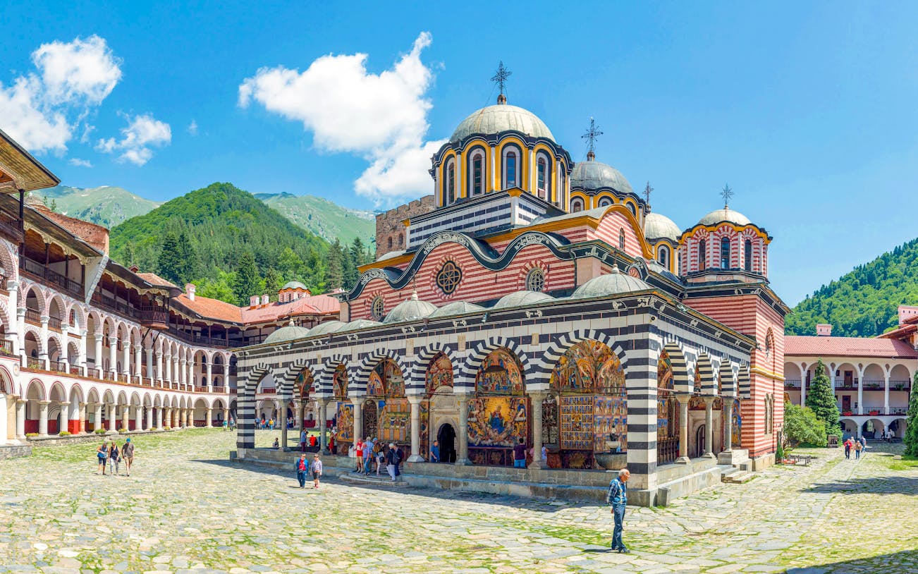 Rila Monastery courtyard with colorful frescoes and domed church, Bulgaria.