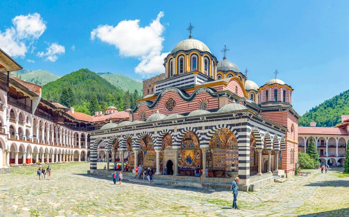 Rila Monastery courtyard with colorful frescoes and domed church, Bulgaria.