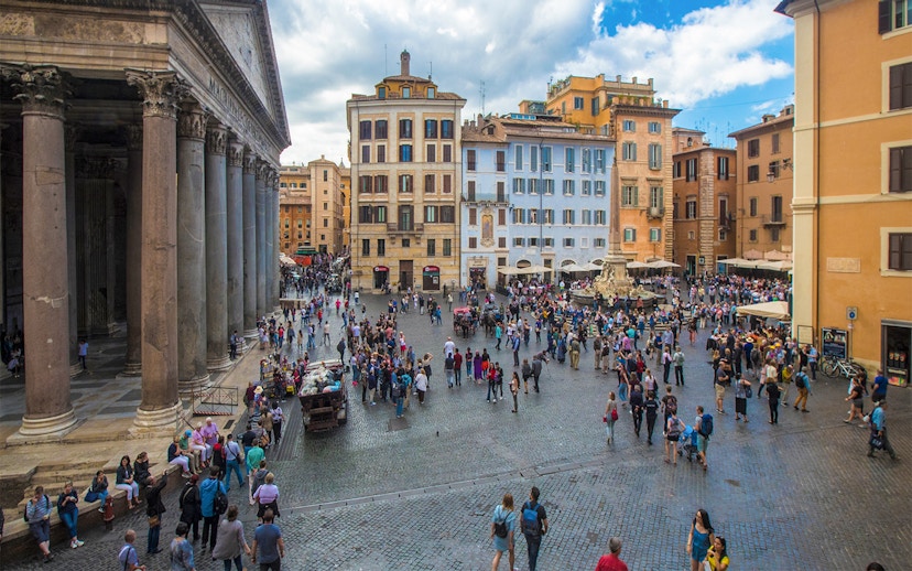 Crowd at Rome's Pantheon Plaza with historic buildings and fountain.