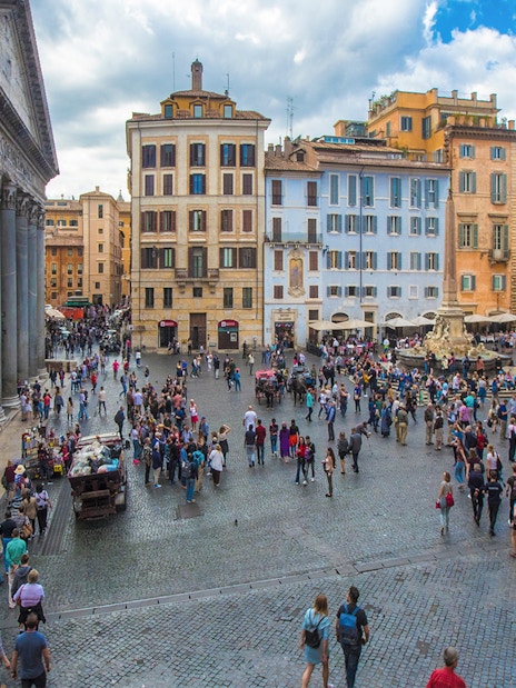 Crowd at Rome's Pantheon Plaza with historic buildings and fountain.