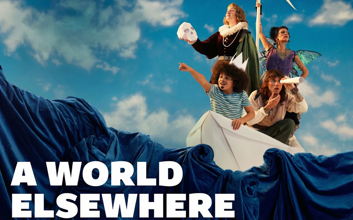 Group on paper boat with costumes, pointing and looking ahead, "A World Elsewhere Westend" theme.