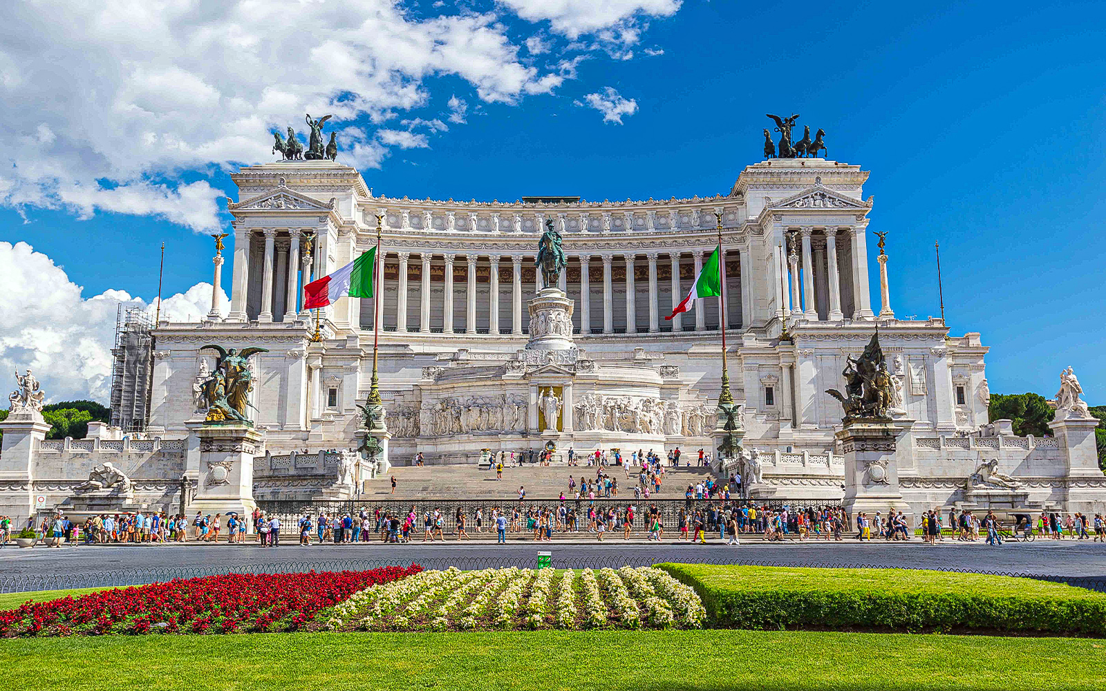 Crowds at the Vittoriano monument in Rome, Italy, with Italian flags and statues.