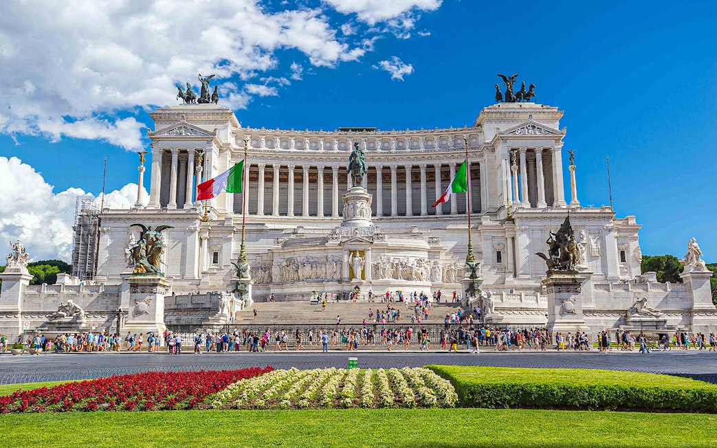 Crowds at the Vittoriano monument in Rome, Italy, with Italian flags and statues.
