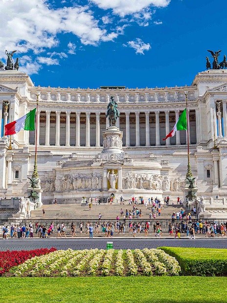 Crowds at the Vittoriano monument in Rome, Italy, with Italian flags and statues.