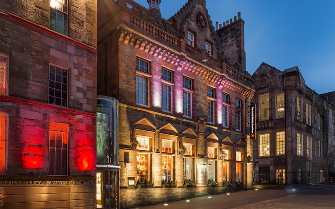 Exteriors of the Scotch Whisky Experience in Edinburgh illuminated at night.