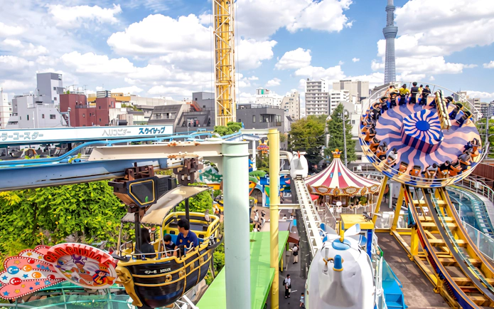 Asakusa Hanayashiki amusement park with rides and Tokyo Skytree in the background.