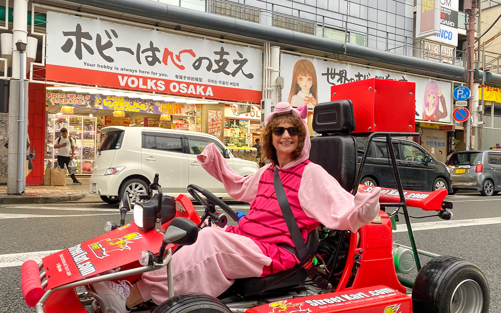 Person in costume driving a go-kart on Osaka Namba street.
