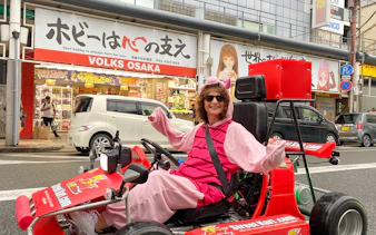 Person in costume driving a go-kart on Osaka Namba street.
