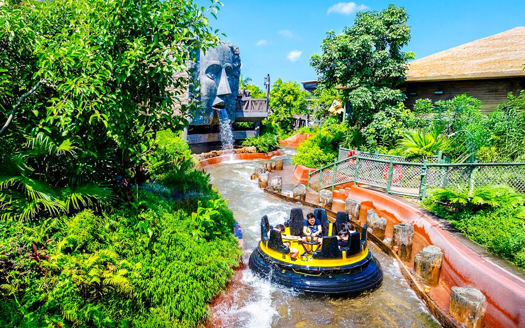 Raft on The Rapids ride at Ocean Park Hong Kong with waterfall and lush greenery.