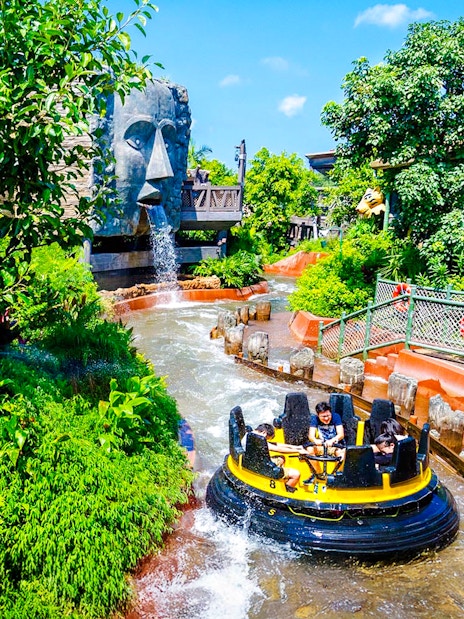 Raft on The Rapids ride at Ocean Park Hong Kong with waterfall and lush greenery.