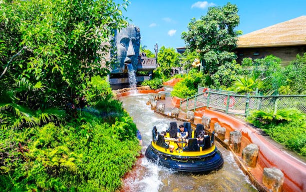 Raft on The Rapids ride at Ocean Park Hong Kong with waterfall and lush greenery.