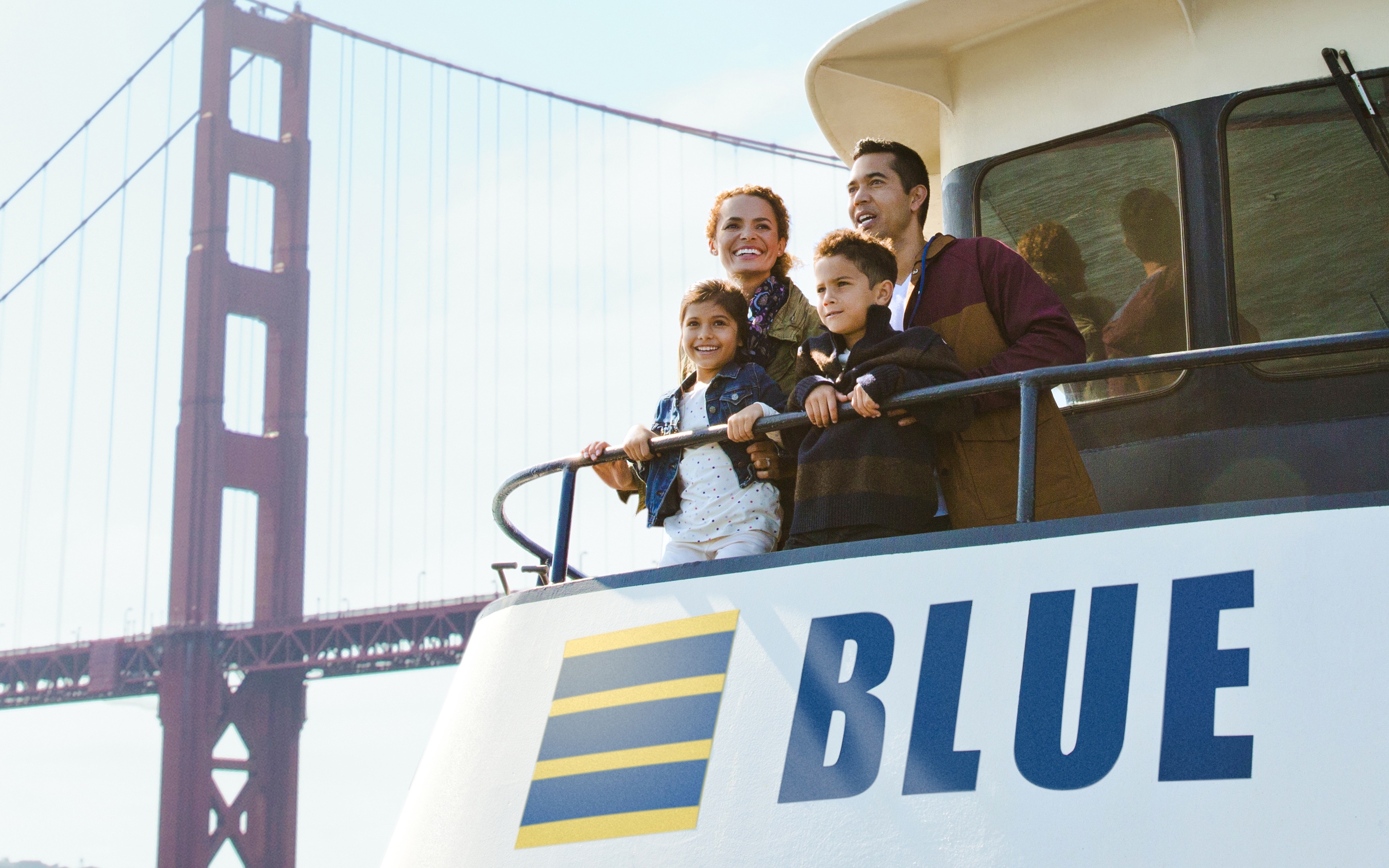 Family enjoying a sunset cruise on San Francisco Bay with Golden Gate Bridge in view.