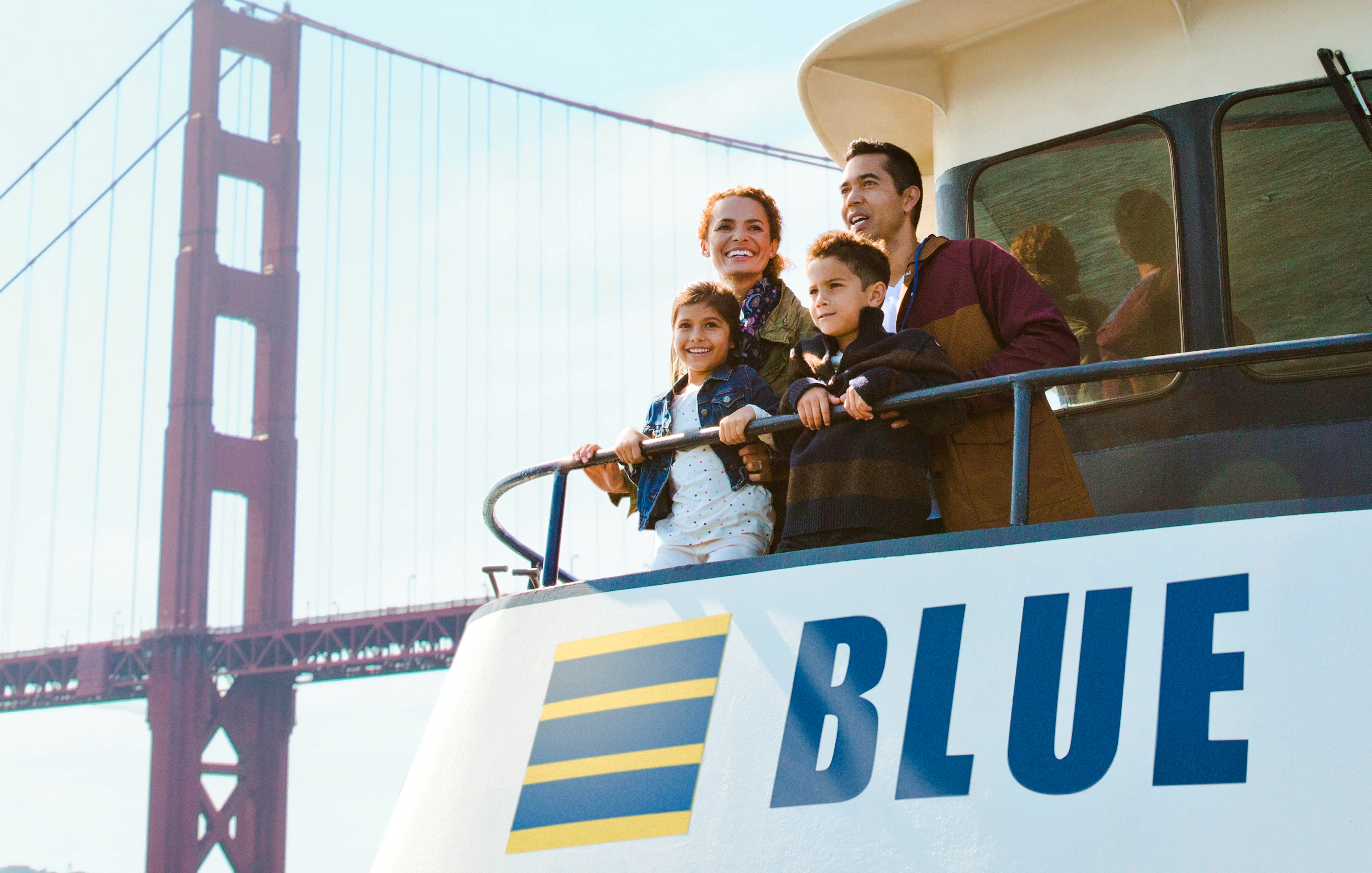 Family enjoying a sunset cruise on San Francisco Bay with Golden Gate Bridge in view.