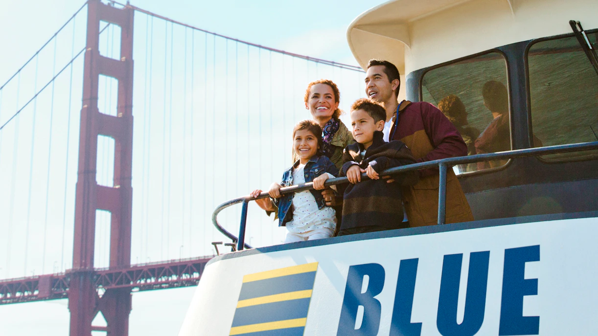 Family enjoying a sunset cruise on San Francisco Bay with Golden Gate Bridge in view.