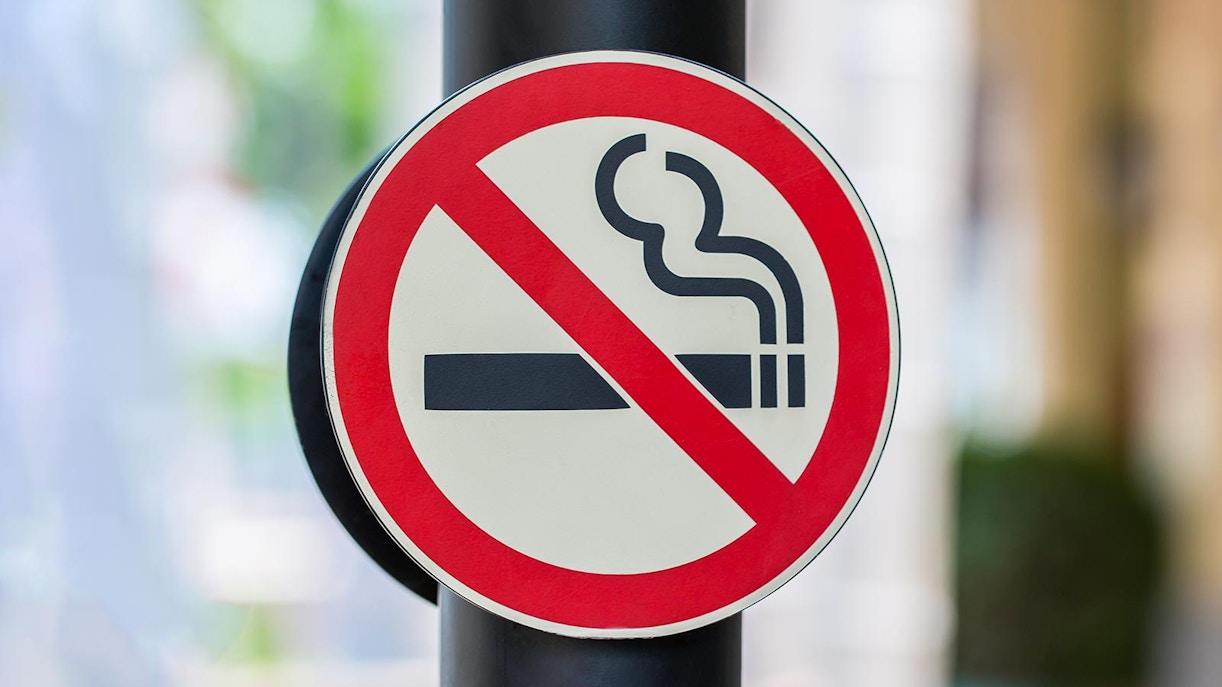 No smoking sign on a pole in an outdoor setting.
