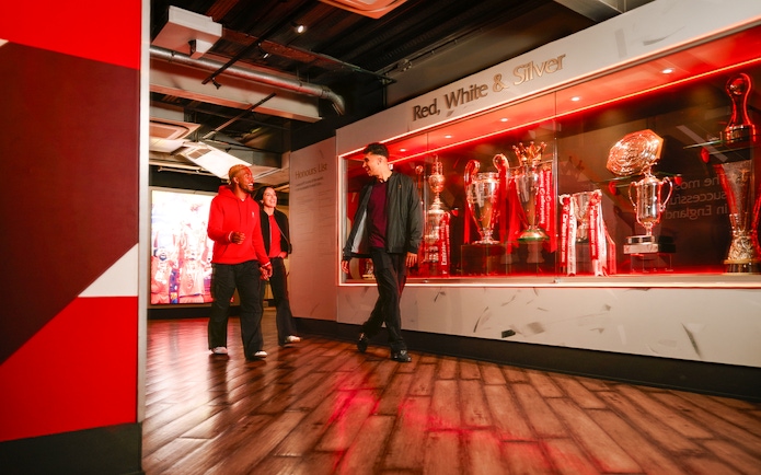 Guests touring Liverpool Football Club Museum trophy display.
