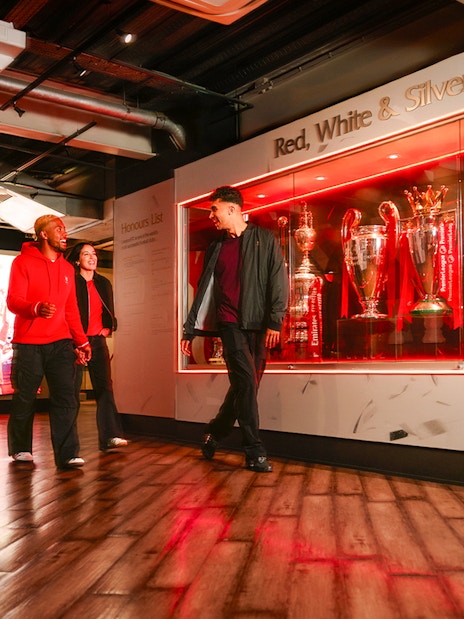 Guests touring Liverpool Football Club Museum trophy display.