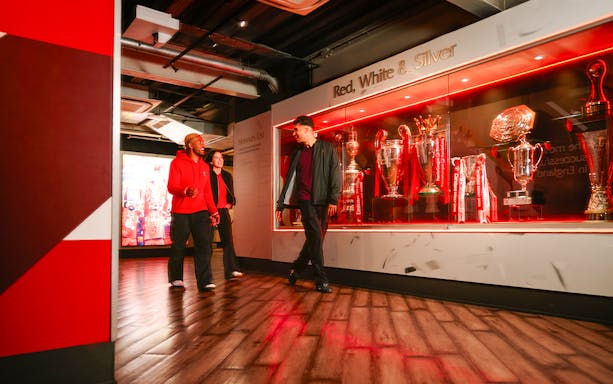 Guests touring Liverpool Football Club Museum trophy display.