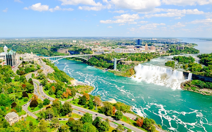 Aerial view of Niagara Falls with surrounding landscape and Rainbow Bridge.