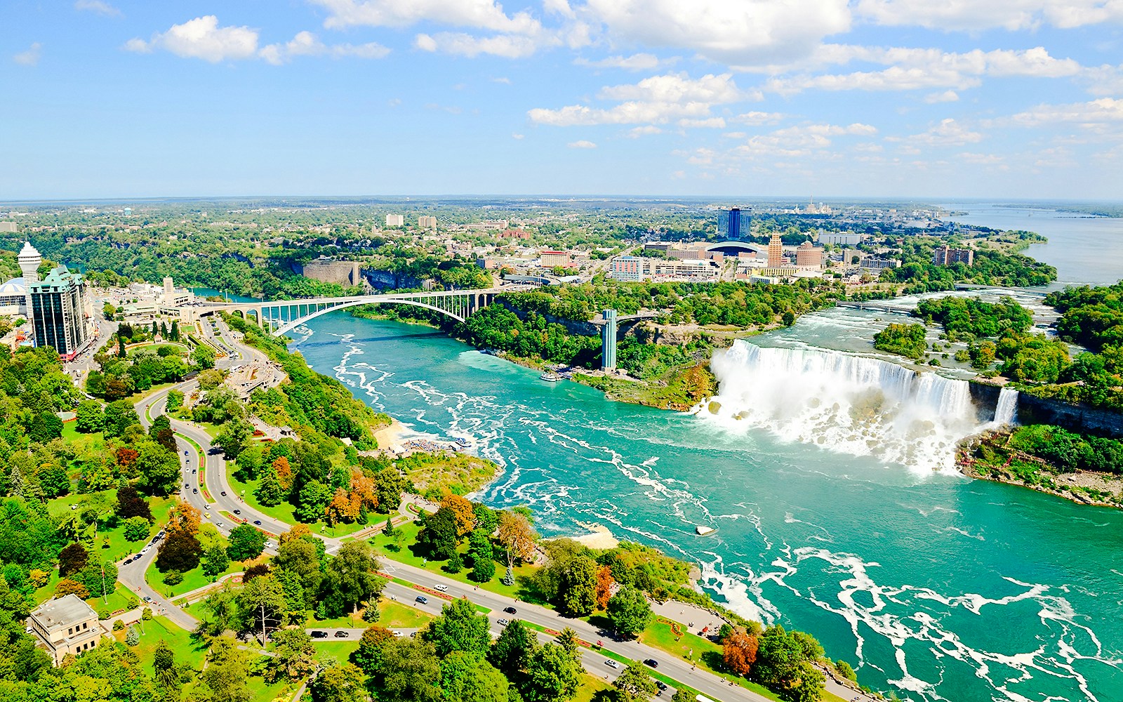 Aerial view of Niagara Falls with surrounding landscape and Rainbow Bridge.