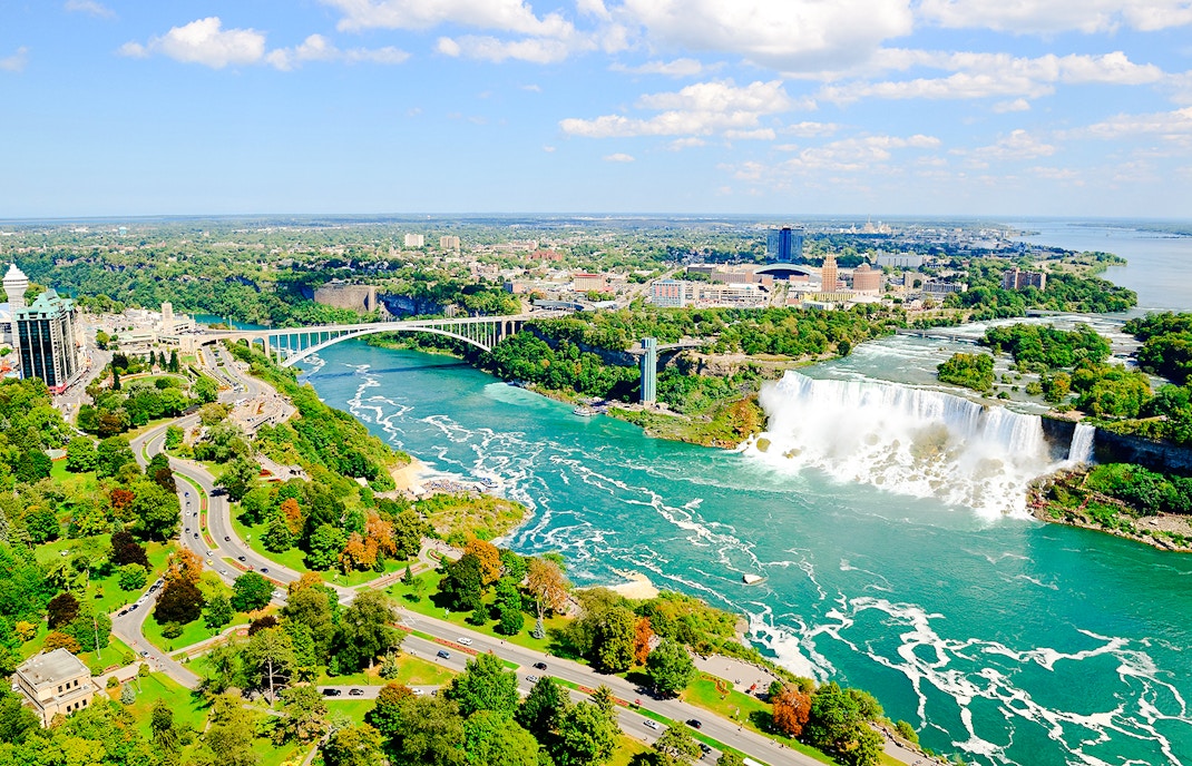 Aerial view of Niagara Falls with surrounding landscape and Rainbow Bridge.