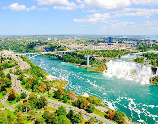 Aerial view of Niagara Falls with surrounding landscape and Rainbow Bridge.
