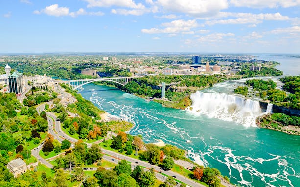 Aerial view of Niagara Falls with surrounding landscape and Rainbow Bridge.