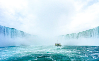 Boat approaching Niagara Falls, Canada amidst mist and cascading water.
