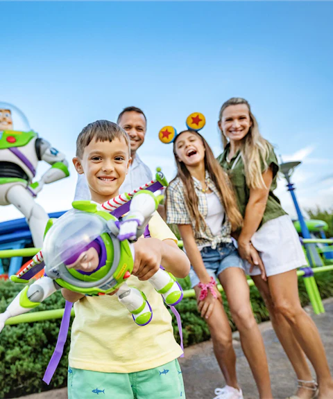 Kid with Buzz Lightyear toy in front of Buzz Lightyear statue at Walt Disney World Resort, Orlando.
